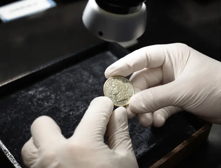 Checking an old silver dollar under a loupe
