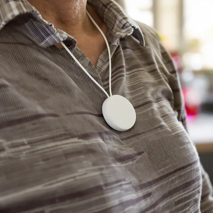 A woman pressing the button on a medical alert pendant