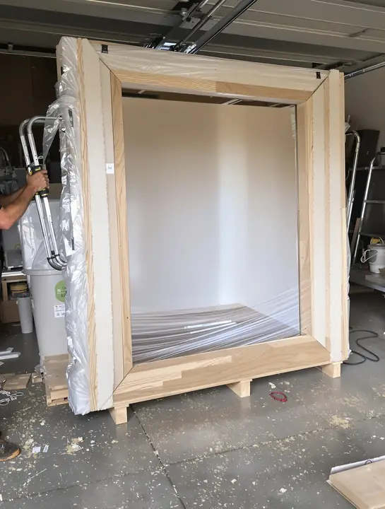 Mover building a wooden crate around a large mirror