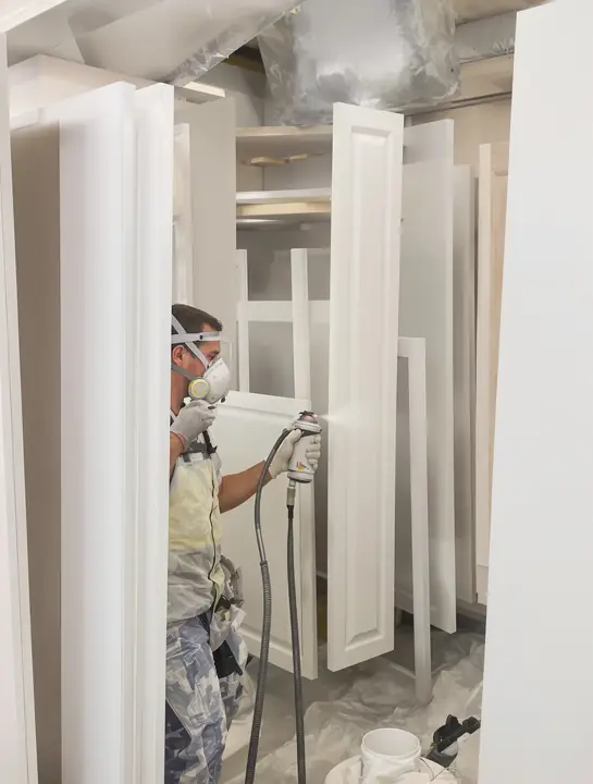 Cabinet doors drying on racks after being sprayed off white in the shop