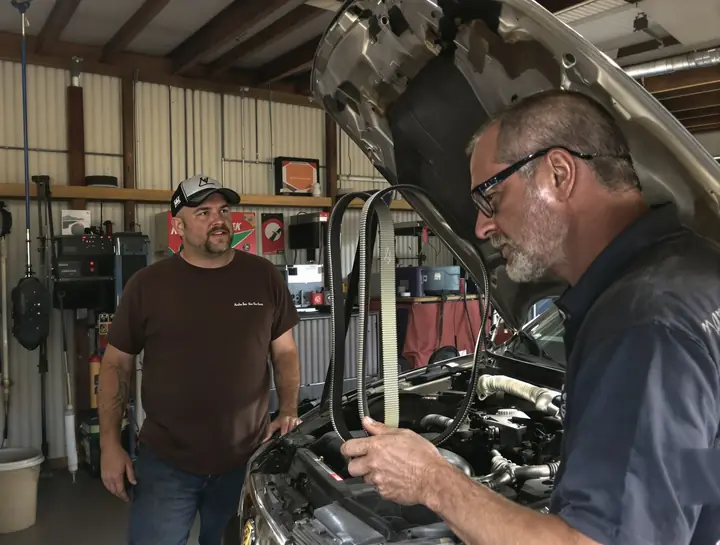 Mechanic showing a worn belt from an older minivan