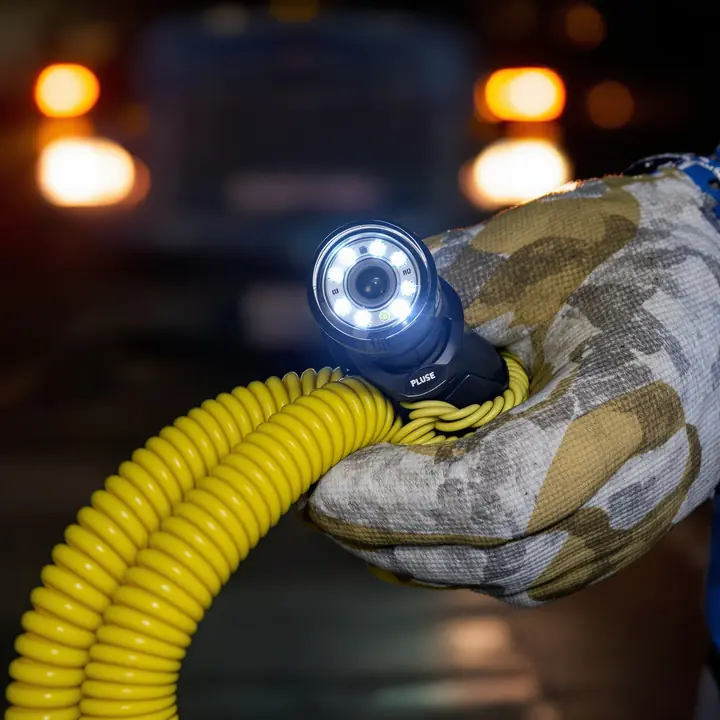 Sewer camera head with bright lights held in a gloved hand
