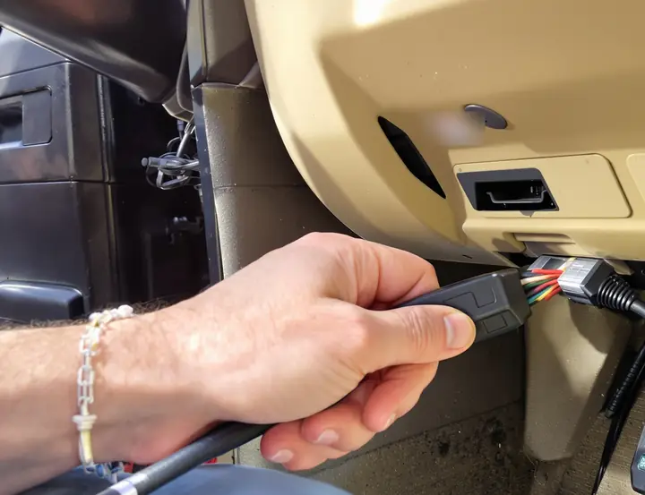 Scan tool cable plugged into the port under the dash