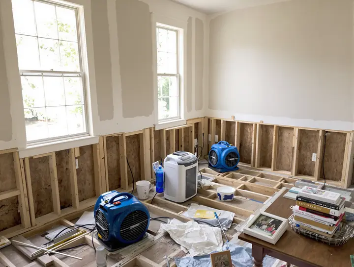 Living room drying out with fans and a dehumidifier, family photos kept safe on a table