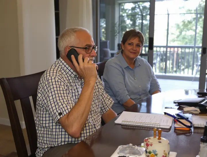 An older man on a counseling call with his daughter beside him