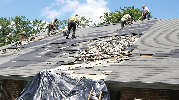Crew tearing off hail damaged shingles on a brick ranch home in Moore