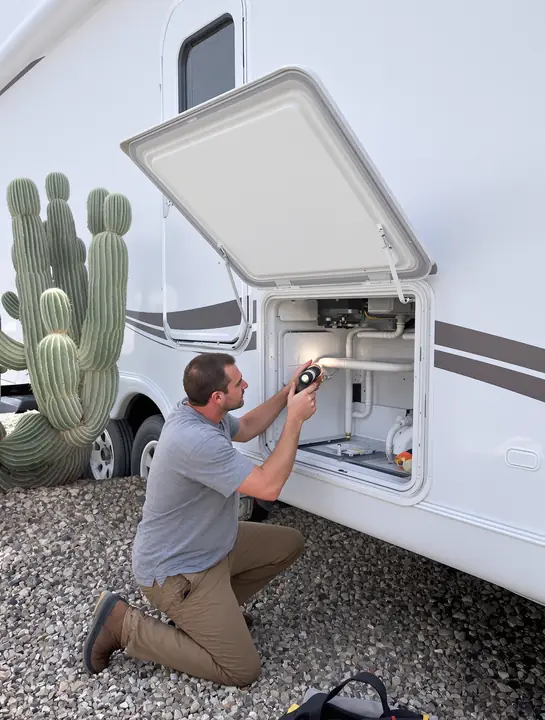 Checking the burner behind the outside fridge vent on a travel trailer