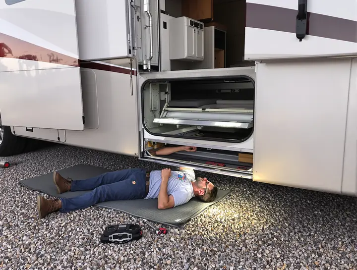 Tech under a class A slide room adjusting the mechanism