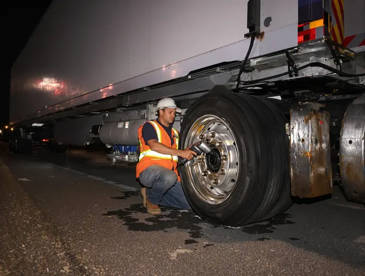 Tech changing a blown steer tire on the shoulder at night