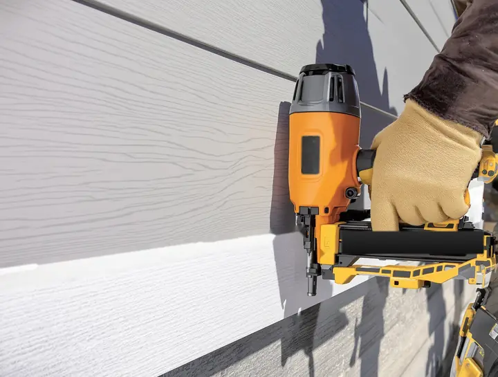 Fiber cement lap boards being nailed along a chalk line