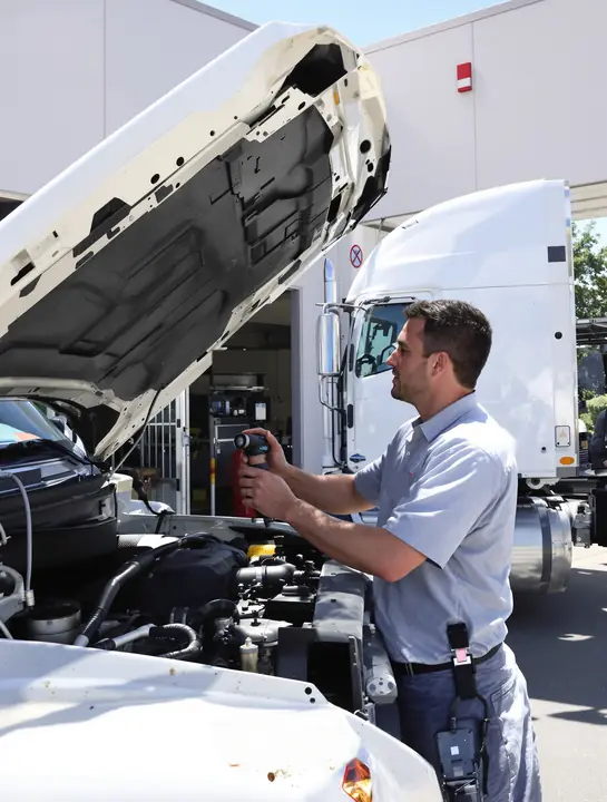 Flashlight check under the hood of a diesel pickup