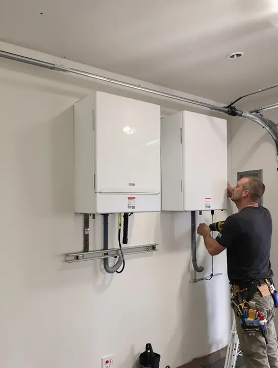 Installer mounting two wall batteries in a garage