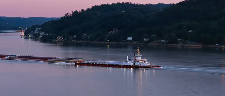 A towboat pushing barges down the Kanawha River at dusk