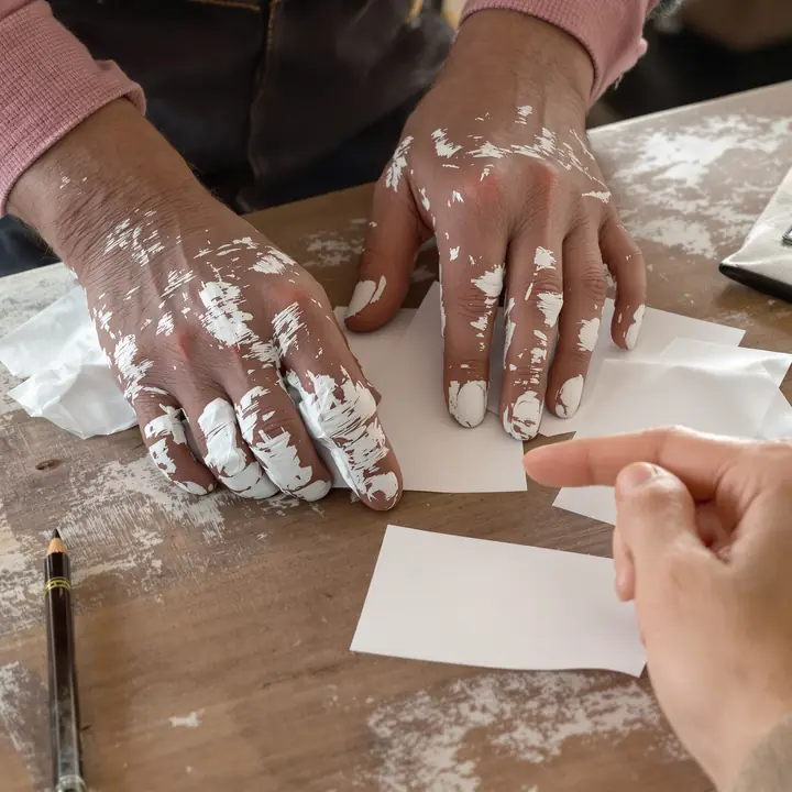 A painter flattening crumpled receipts on a desk next to a calculator