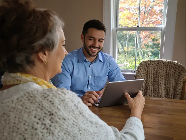 Technician showing an older woman how to start a video call on her tablet