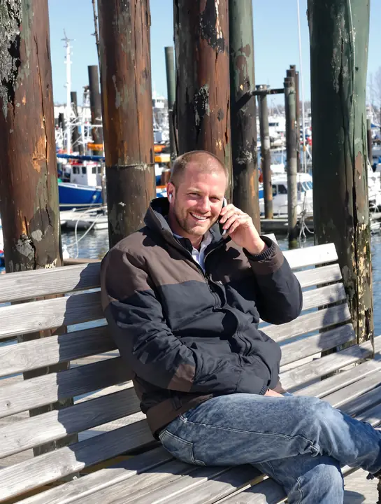 Man on a phone call on a bench at a Portland wharf