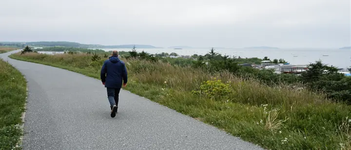 Man walking the Eastern Promenade trail above Casco Bay in the morning