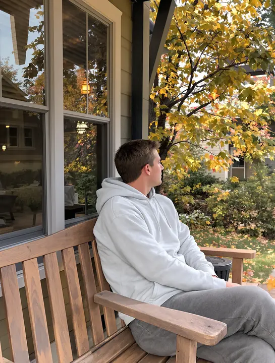 Teen sitting on a porch bench under autumn leaves in Boulder