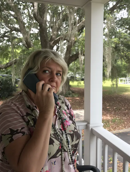A worried owner on her porch taking a call about her timeshare