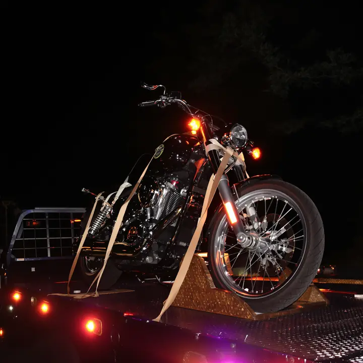 Motorcycle strapped upright on a flatbed at night