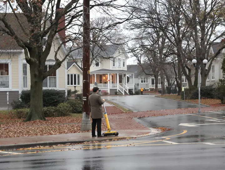 Investigator measuring a curb at a quiet Akron intersection